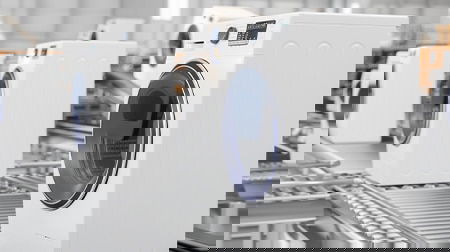 Washing machines lined up on a conveyor belt.