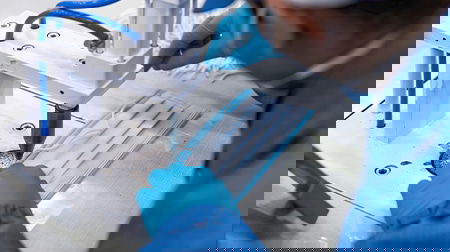 Person wearing medical clothing working on medical equipment.