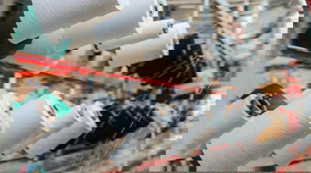 Multiple spools of thread and rows of equipment in a textile factory.